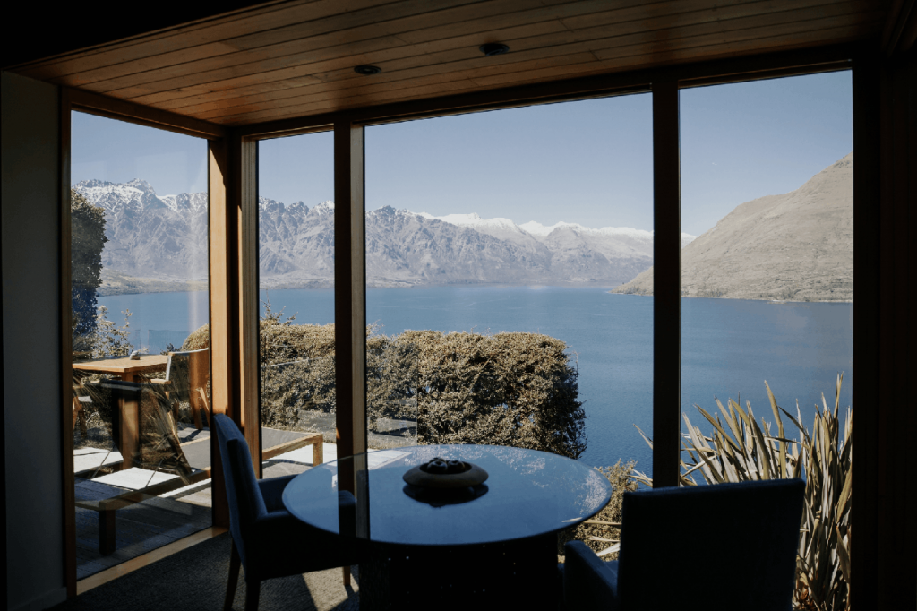 Image of lounge and balcony in the foreground and Lake Wakatipu and mountains in the background.