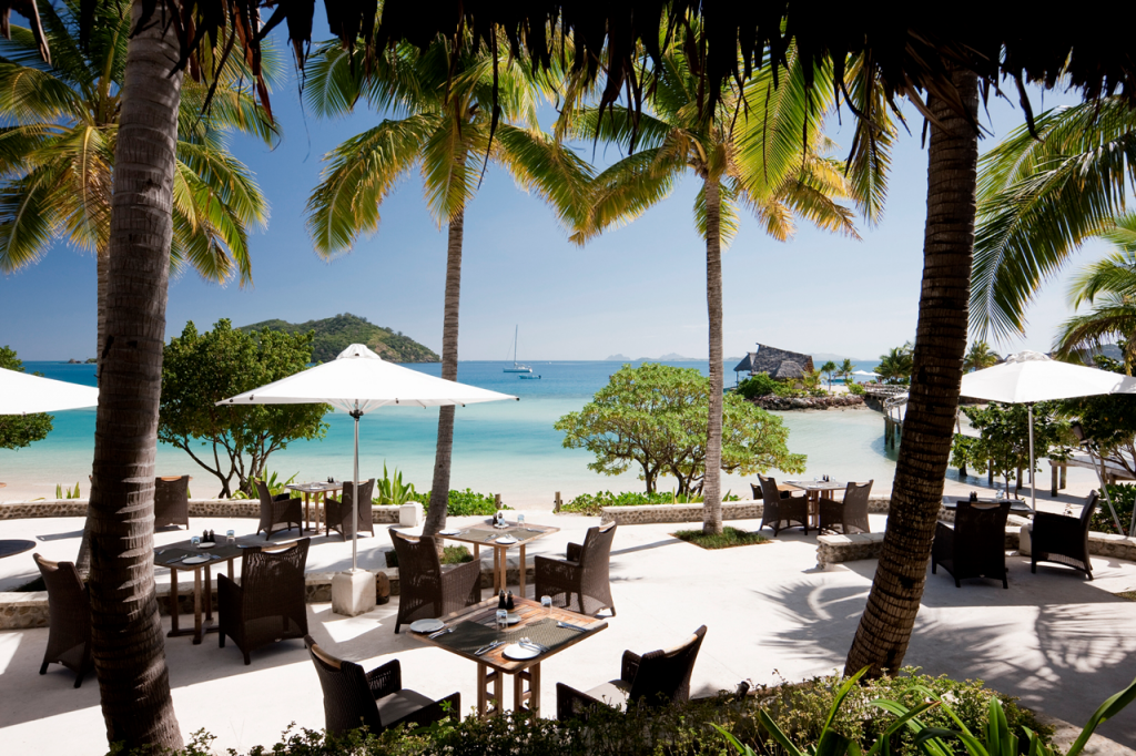 In the foreground is the patio dining area with the lagoon in the background.