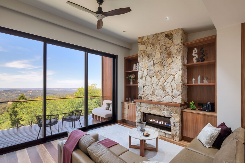 Image of a Sequoia Lodge suite lounge in the foreground, balcony and sweeping view over hills and forest in the background.